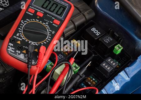 Auto service, repair and maintenance concept - digital multimeter or voltmeter testing car battery. Stock Photo