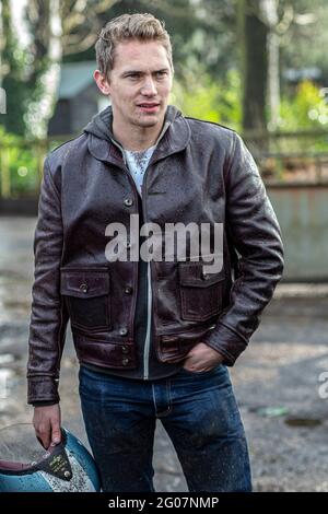 Man wearing leather jacket and carrying motorcycle helmet . Stock Photo