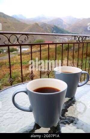 Closeup Two Cups of on the Table with Blurry Countryside View in Background Stock Photo