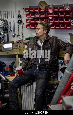 Portrait of a man in workshop on his break drinking tea or coffee. Mechanic having coffee break in his garage. Stock Photo