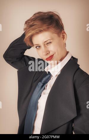 Winking business woman in black suit with tie. Looking at camera, toned image Stock Photo