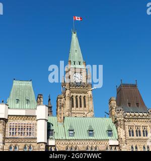 Ottawa, Canada - May 23, 2021: Parliament building with canadian flag in the capital of Canada, Ottawa against blue sky. Side view. Parliament hill. Stock Photo