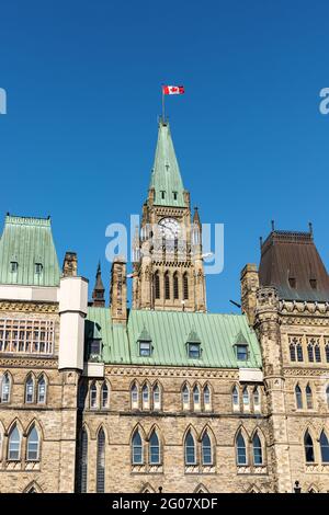 Ottawa, Canada - May 23, 2021: Parliament building with canadian flag in the capital of Canada, Ottawa against blue sky. Side view. Stock Photo