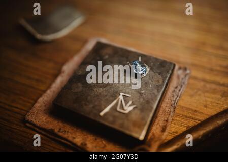 Closeup shiny blue gemstone for jewellery placed on metal plate on wooden workbench Stock Photo