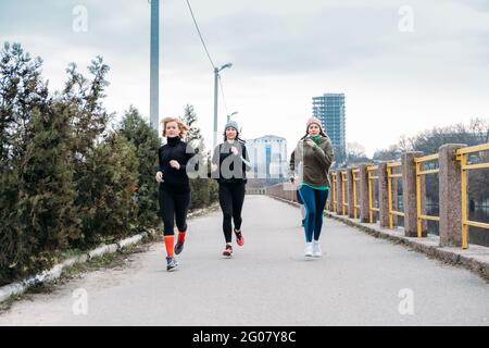 Young and middle aged sports people group running in the urban environment. Group of runners in the park in the fall autumn spring morning. Group of Stock Photo