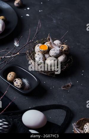 From above composition of raw chicken eggs on plates and quail eggs in nest on black background Stock Photo