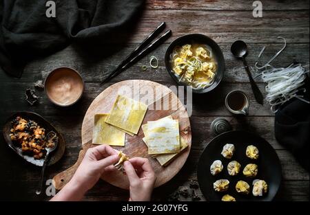 Top view of anonymous Woman preparing wonton soup on a wooden table Stock Photo