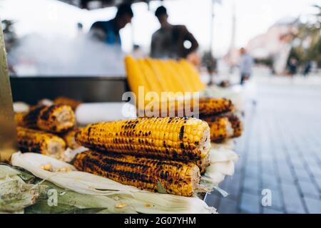 Fresh raw and fried corn cobs arranged on stall of street diner against steamy pot in city in Turkey Stock Photo