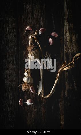 From above bouquet of fresh purple garlic cloves placed in dark wooden background Stock Photo