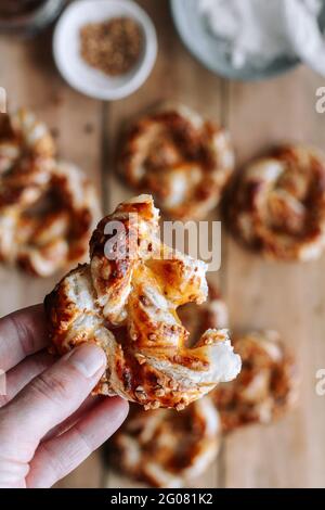 Top view of unrecognizable person taking delicious pretzel with fig jam and cream cheese from lumber table in kitchen Stock Photo