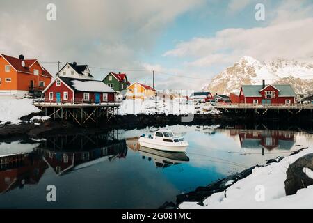 Snowy quay in peaceful coastal settlement with red houses on cloudy winter day on Lofoten Islands, Norway Stock Photo