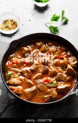 Stewed chicken livers in frying pan over dark stone background. Stock Photo