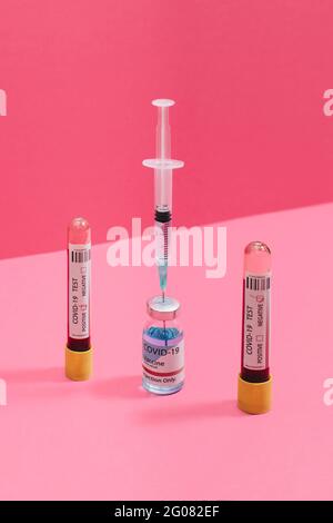 Coronavirus negative and positive blood test near vaccine flask and syringe on pink background Stock Photo