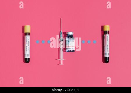 From above coronavirus negative and positive blood test near vaccine flask and syringe on pink background Stock Photo