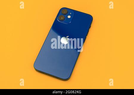 Kharkov, Ukraine - May 28, 2021: Apple iPhone 12 Mini Pacific Blue color, back side of a new modern mobile phone on a office table, orange background Stock Photo