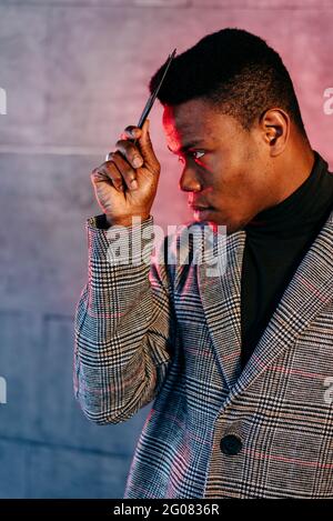Portrait of elegant black man with grey coat combing in the street Stock Photo