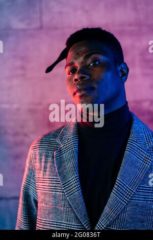 Portrait of elegant black man with grey coat combing in the street Stock Photo