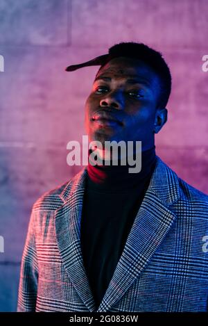 Portrait of elegant black man with grey coat combing in the street Stock Photo