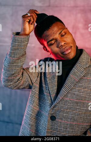 Portrait of elegant black man with grey coat combing in the street Stock Photo