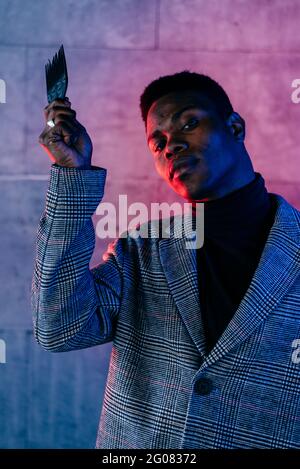 Portrait of elegant black man with grey coat combing in the street Stock Photo