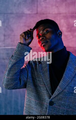 Portrait of elegant black man with grey coat combing in the street Stock Photo