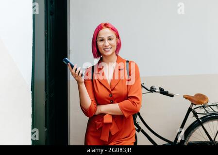 Full body of cheerful young female smiling and looking away near old bicycle with timber wicker basket Stock Photo