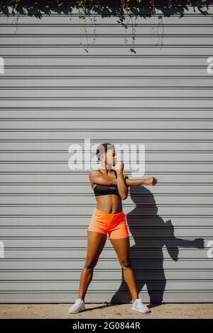 Young fitness African American Woman stretching arms before running on city street Stock Photo