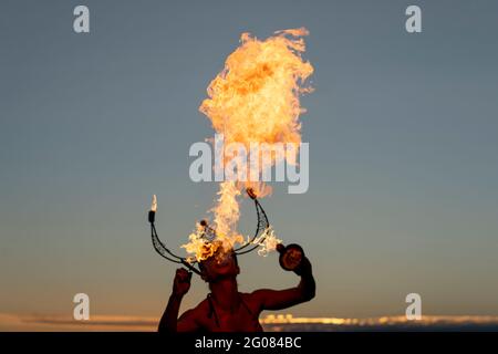 Fire-Eater Woman Performing Spit Fire At Sunset Stock Photo