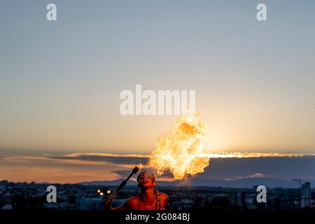 Fire-Eater Woman Performing Spit Fire At Sunset Stock Photo