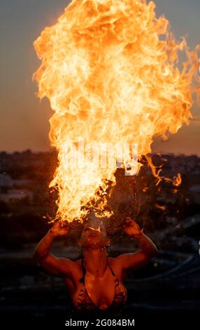 Fire-Eater Woman Performing Spit Fire At Sunset Stock Photo