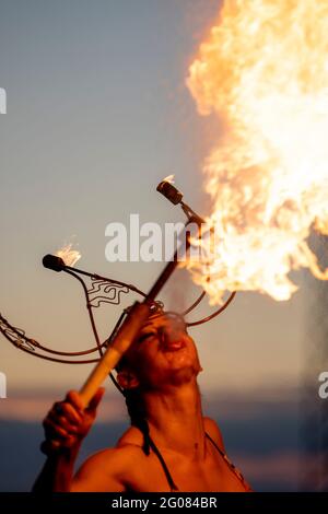 Fire-Eater Woman Performing Spit Fire At Sunset Stock Photo