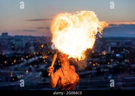 Fire-Eater Woman Performing Spit Fire At Sunset Stock Photo