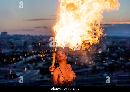 Fire-Eater Woman Performing Spit Fire At Sunset Stock Photo