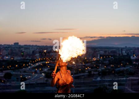 Fire-Eater Woman Performing Spit Fire At Sunset Stock Photo