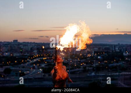 Fire-Eater Woman Performing Spit Fire At Sunset Stock Photo