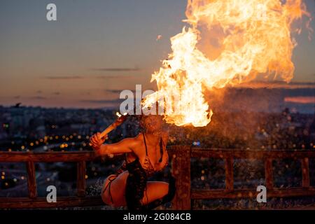 Fire-Eater Woman Performing Spit Fire At Sunset Stock Photo