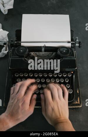 From above shot of hands of anonymous person typing on keyboard of vintage typewriter Stock Photo