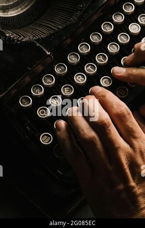 From above shot of hands of anonymous person typing on keyboard of vintage typewriter Stock Photo