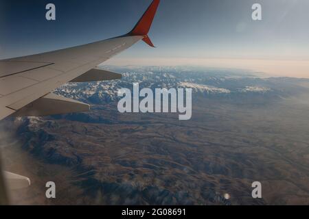 Beautiful view from airplane porthole of snowy mountains Stock Photo