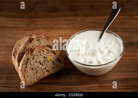 A bowl with cottage cheese and slices of bread on a wooden board Stock Photo