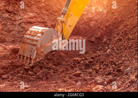 Backhoe working by digging soil at construction site. Bucket of backhoe digging soil. Crawler excavator digging on dirt. Closeup backhoe bucket. Stock Photo