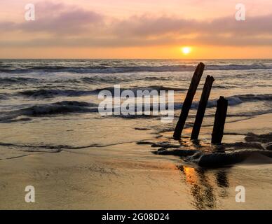 Sunset over ruined old pier pilings at Fort Funston Beach. San Francisco, California, USA. Stock Photo