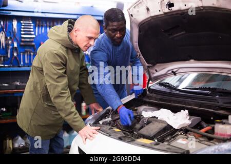 Owner of car explains the problem with car engine to mechanic of the car service Stock Photo