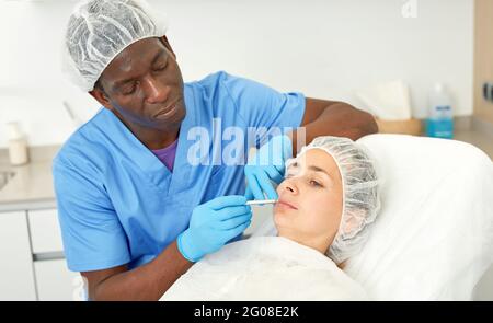Dermatologist male preparing woman client before aesthetic facial procedure Stock Photo
