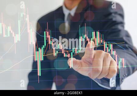 business man wearing a suit pointing fingers stock marketing finance on modern virtual interface. Stock Photo