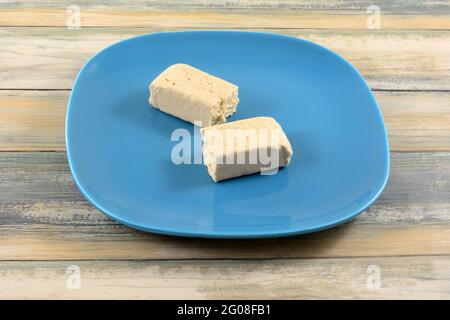 Two pieces of vanilla tahini halvah snack on blue snack plate Stock Photo