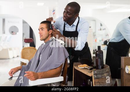 African hairdresser doing styling for young man Stock Photo