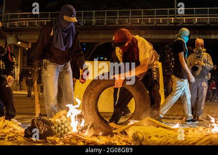 Medellin, Colombia on May 31, 2021. Demonstrators make a barricade with burnt tires and trash to prevent riot armored trucks from approaching and the effects of tear gas as a group of hooded demonstrators clashes with Colombia's riot police (ESMAD) in Medellin, Colombia during the on going anti government protests against Presiden Ivan Duque's tax and health reform and police brutality and unrest that leaves at least 70 dead during the past month, in Medellin, Colombia on May 31, 2021. Stock Photo