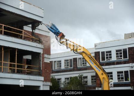 GREYMOUTH, NEW ZEALAND, January 19, 2021: An excavator uses a claw attachment to demolish the old hospital building in Greymouth, New Zealand, January Stock Photo
