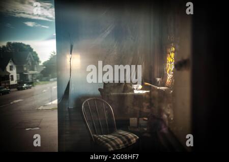 Old wooden chair reflected in a window, old houses in background Stock Photo